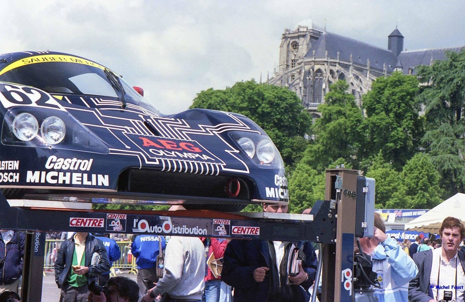 Mercedes-Benz C9 Group C race car at Le Mans scrutineering, with Le Mans Cathedral in the background